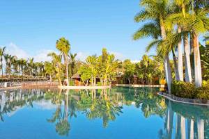 Ein großer Swimmingpool im Tabaiba Princess Hotel, umgeben von Palmen und Liegestühlen.