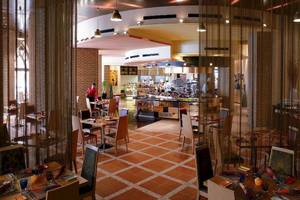Innenansicht des Restaurants im Shangri-La Barr Al Jissah Resort & Spa mit gefliestem Boden und gedeckten Tischen.