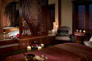Massageraum im Shangri-La Barr Al Jissah Resort & Spa mit Whirlpool, Kerzen und Möbeln.