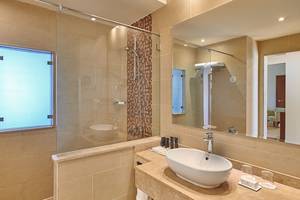 Badezimmer im Steigenberger Aqua Magic Hotel mit großer Glasdusche, Waschbecken und Spiegel.
