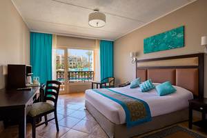 Hotelzimmer im Steigenberger Aqua Magic mit Bett, Schreibtisch, Stühlen, Fernseher und Balkon.