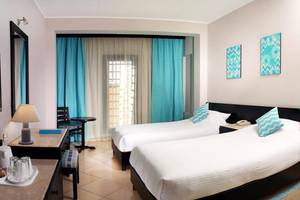 Doppelzimmer im Steigenberger Aqua Magic Hotel mit zwei Betten, Fernseher, Schreibtisch und Dekoration.