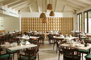 Innenbereich eines Restaurants im Cretan Malia Park Hotel mit runden Holzlampen und geometrischen Wandverkleidungen.