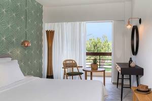 Ein elegantes Bettzimmer im Cretan Malia Park Hotel mit einem Balkon und grünen Wänden.