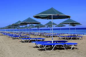 Reihe von Sonnenliegen und Sonnenschirmen am Strand des Blue Bay Beach Resorts.