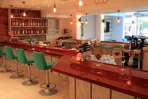 Bar im Blue Bay Beach Resort Hotel mit grünen Stühlen und einer Theke.