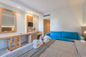 Zimmer im Tigaki Beach Hotel mit Bett, Couch, Schreibtisch und Fernseher