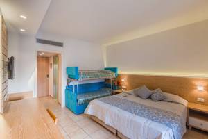 Zimmer im Hotel Tigaki Beach mit einem Doppelbett und einem Etagenbett, eingerichtet mit hellen Farben.