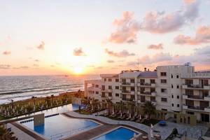 Sonnenuntergang am Capital Coast Resort & Spa mit Blick auf das Meer und den Poolbereich.