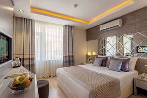 Schlafzimmer im Turan Prince Hotel mit Bett, Obstschale und Fernseher.