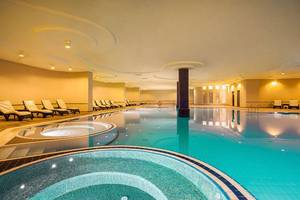 Schwimmbecken im Turan Prince Hotel mit Liegestühlen und gelben Wänden.