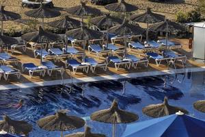 Poolbereich des VIK Hotels San Antonio mit vielen Liegestühlen und Sonnenschirmen.