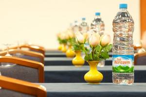 Konferenzraum im Le Meridien N'Fis Hotel mit blauen Tischen, weißen Rosen in gelben Vasen und Wasserflaschen.