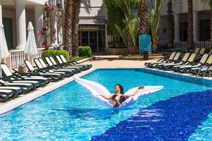 Frau auf einem großen weißen Schwimmtier im Pool des Alba Queen Hotels