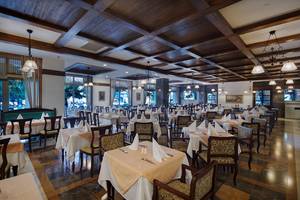 Innenansicht des Restaurants im Alba Queen Hotel mit vielen gedeckten Tischen und Holzdecken.