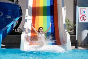Junge Frau rutscht auf einer Regenbogenrutsche im Alba Queen Hotel.