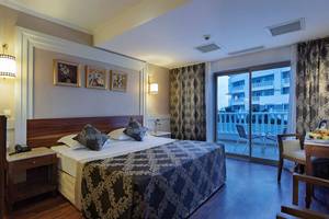 Hotelzimmer im Alba Queen Hotel mit Doppelbett, Balkon und Blick auf ein Gebäude.
