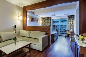 Innenansicht eines Zimmers im Alba Queen Hotel mit Sofa, Tisch, Balkon und Bett