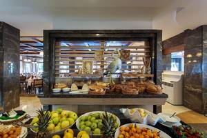 Buffet-Tisch im Alba Queen Hotel mit verschiedenen Broten, Obst und Desserts.