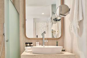 Badezimmer im Myconian Kyma Hotel mit Dusche, Waschbecken und Spiegel.