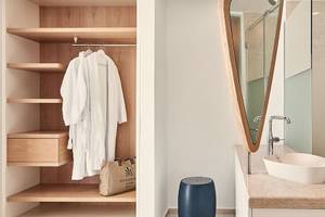 Badezimmer mit offenem Kleiderschrank, Robe, und Waschbecken im Hotel Myconian Kyma.