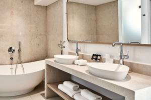 Das Badezimmer des Myconian Kyma Hotels mit einer Badewanne und zwei Waschbecken.