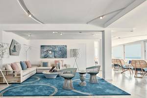 Innenbereich des Myconian Kyma Hotels mit weißem Sofa, blauem Teppich und modernen Möbeln.