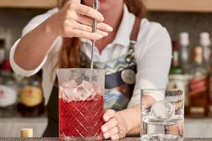 Frau mischt einen Cocktail am Tresor Bar im Myconian Kyma Hotel