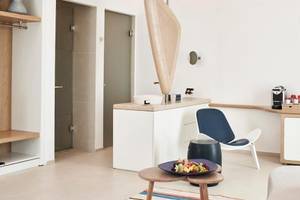 Inneneinrichtung eines Zimmers im Myconian Kyma Hotel mit modernem Design, weißem Wand und Boden, Möbeln und Dekor.