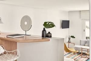 Innenbereich des Myconian Kyma Hotels mit heller Wand, Schreibtisch, Lampe, Dekor und Pflanzen.