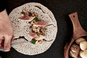 Ein Teller mit Essen von Myconian Kyma, bestehend aus Fisch, Bohnen und anderen Zutaten.