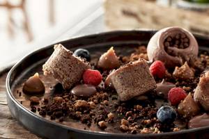 Schokoladen-Dessert-Platte im Myconian Kyma Hotel mit verschiedenen Früchten und Schokoladenstücken.