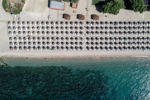 Luftaufnahme des Mitsis Blue Domes Resorts mit vielen Sonnenliegen am Strand