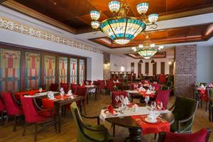 Innenansicht des Restaurants im Well Palace Side Hotel mit kunstvollen Kronleuchtern und farbigen Glasfenstern.