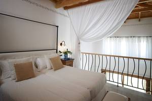 Schlafzimmer im Mitsis Blue Domes Resort mit weißem Bett, Dekor und Balkon
