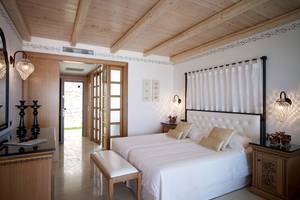 Schlafzimmer im Mitsis Blue Domes Resort & Spa mit Holzdecke, weißen Wänden und zwei Betten.