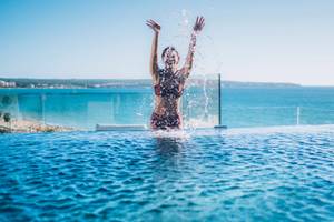 Frau im roten Bikini spritzt Wasser im Pool des Iberostar Selection Playa de Palma