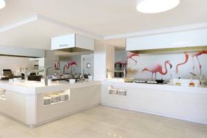 Speisebereich im Iberostar Selection Playa de Palma Hotel mit Flamingo-Wandgemälde und weißen Möbeln.
