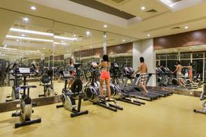 Innenansicht des Fitnesscenters im Well Palace Side Hotel mit mehreren Cardiogeräten und spiegelnden Wänden.