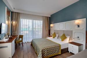 Hotelzimmer im Well Palace Side mit Bett, Schreibtisch und Fernseher.