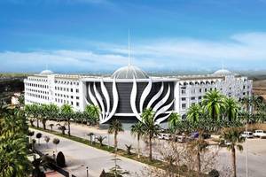 Außenansicht des Defne Defnem Hotels mit moderner Architektur und palmenbestandener Einfahrt.