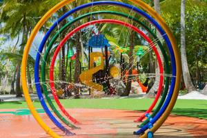 Spielplatz im Dhigali Maldives mit bunten Wasserspielkreisen und Palmen im Hintergrund.