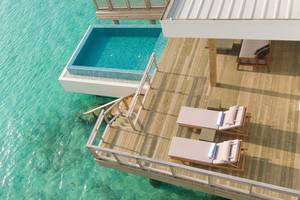 Luftaufnahme des Dhigali Maldives mit Swimmingpool über dem Wasser und Loungebereich mit Liegen.