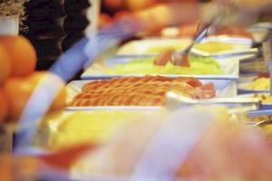 Buffet-Tisch mit verschiedenen Obstsorten und Lebensmitteln, teilweise in weißen Tellern.