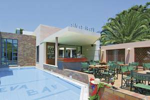 Außenbereich des Eva Bay Hotels mit Pool, Bar und Terrassenmöbeln.