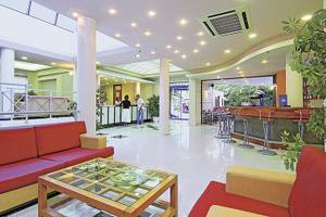 Empfangsbereich des Eva Bay Hotels mit roten Sofas, Bar und Empfangstresen.