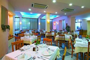 Innenansicht des Restaurants im Eva Bay Hotel mit gedeckten Tischen und farbiger Beleuchtung.
