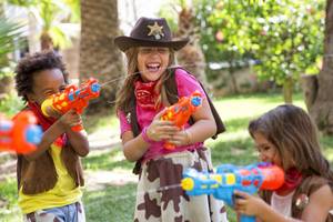 Drei Kinder spielen mit Wasserpistolen im Garten des Sol Principe Hotels.