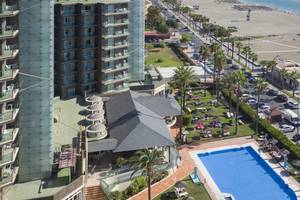 Außenansicht des Sol Principe Hotels mit Swimmingpool, Sonnenliegen und Palmen vor der Küste