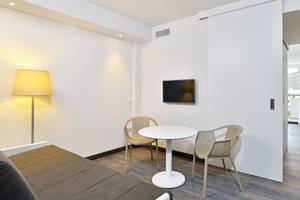 Ein modernes Hotelzimmer von Sol Principe mit weißem Tisch, Stühlen und Fernseher an der Wand.
